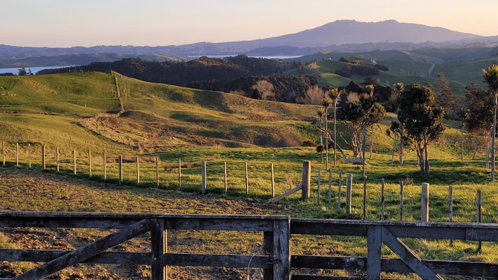 a farm image of a wooden fence with rolling green hills